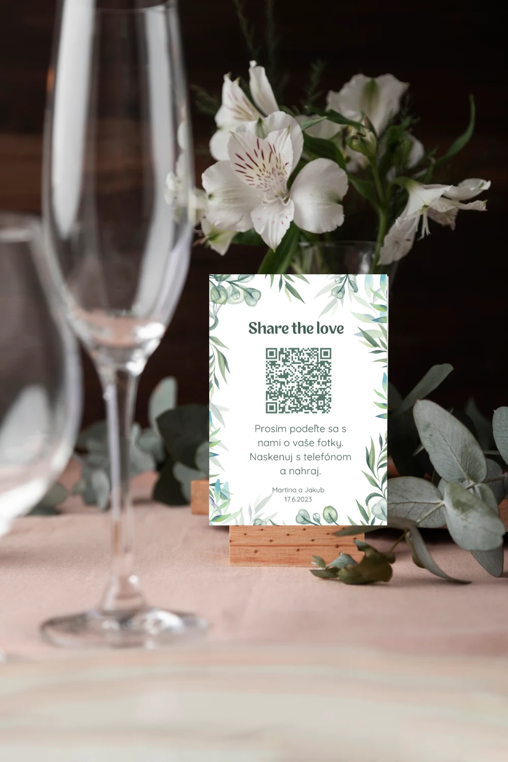 Svadobná kartička s QR kódom na stole medzi kvetmi a pohármi